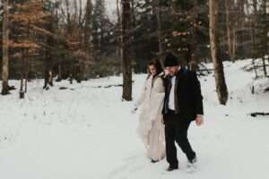 bride and groom hiking in snow on elopement day