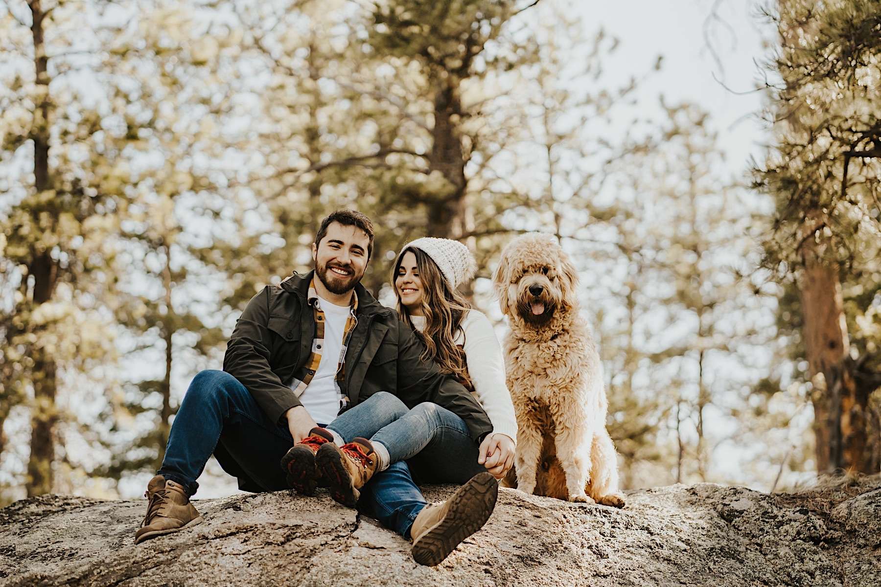 couple sitting on rock in colorado with dog next to them