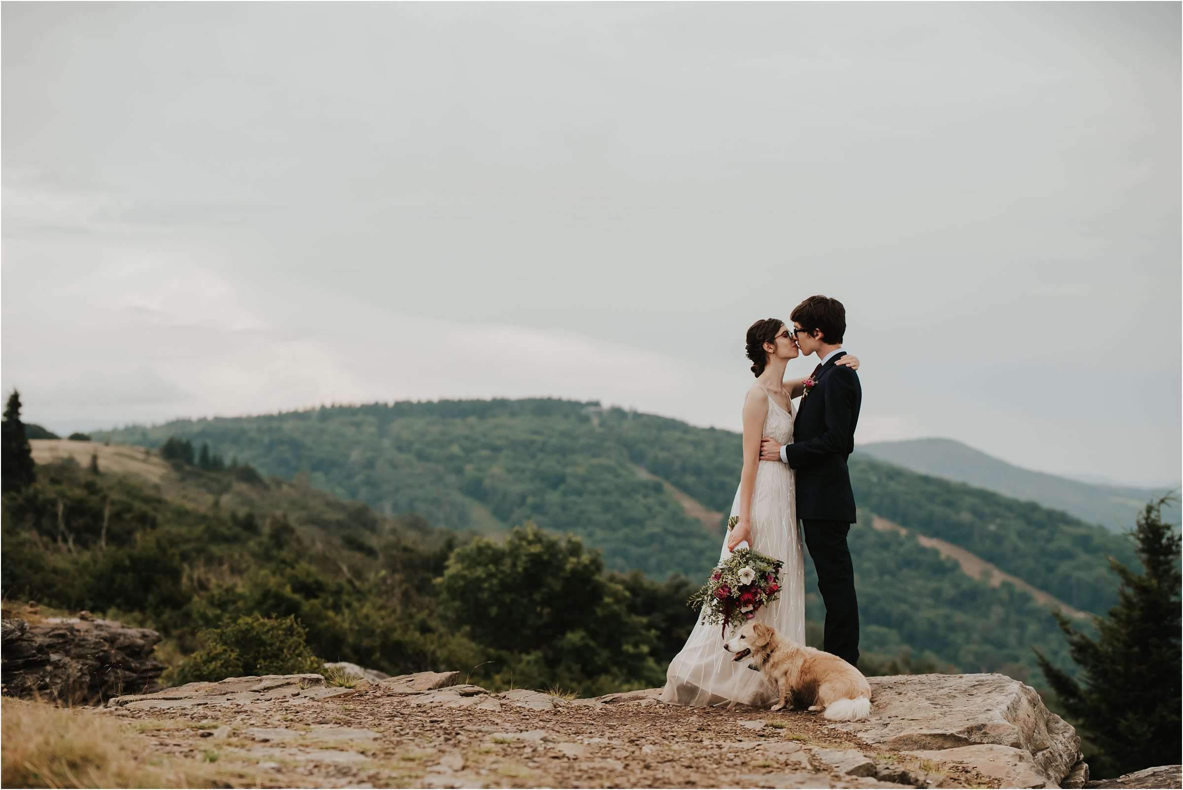 bride and groom on top of mountain hugging with dog at elopement