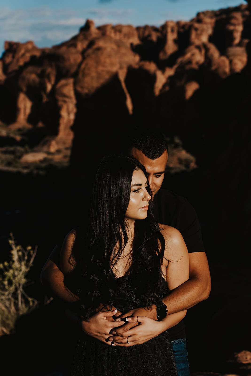 Couple wearing black at Arches National Park hugging in the morning sun