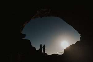 couple holding hands as a silhouette in the windows at arches national park in moab